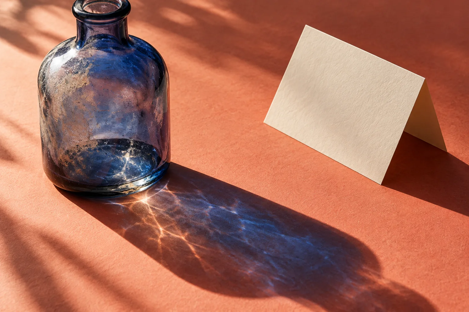 Cloudy glass casts a cobalt shadow over coral paper